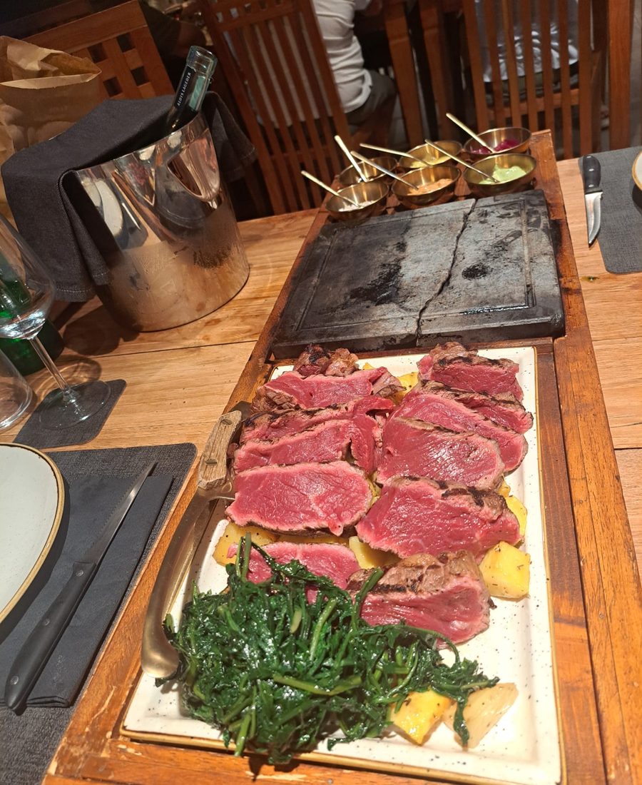 Tagliere di legno con fettine sottili di carne cruda, cicoria ripassata e crostini