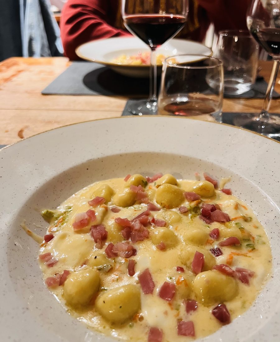 Piatto fondo di gnocchi di patate in crema di formaggio con dadini di prosciutto crudo